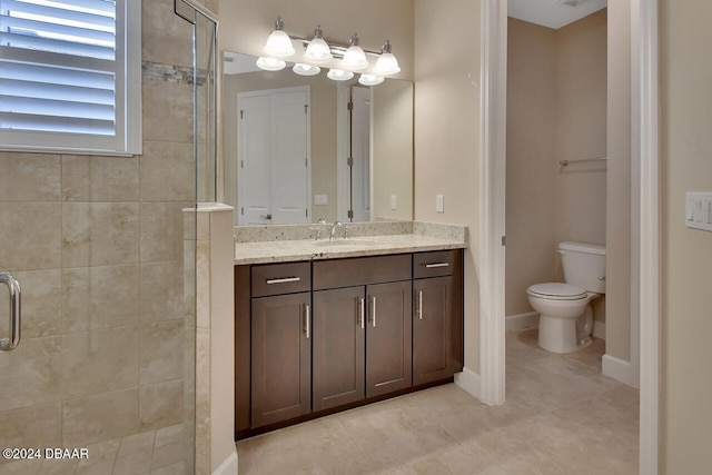 bathroom with an enclosed shower, vanity, toilet, and tile patterned flooring