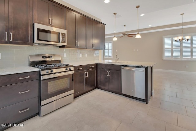 kitchen featuring pendant lighting, stainless steel appliances, ceiling fan with notable chandelier, and sink