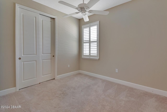 unfurnished bedroom with ceiling fan, a closet, and light carpet