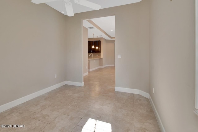 tiled empty room featuring ceiling fan and sink