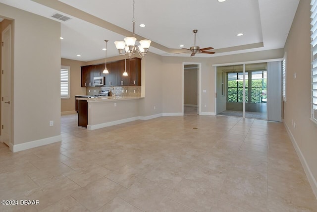 kitchen with kitchen peninsula, backsplash, dark brown cabinets, ceiling fan with notable chandelier, and stainless steel appliances