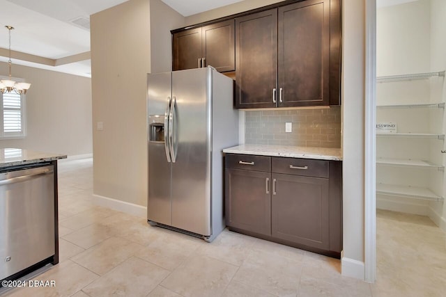 kitchen featuring pendant lighting, light stone countertops, appliances with stainless steel finishes, dark brown cabinetry, and a chandelier