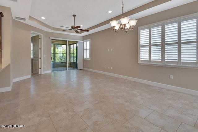 tiled spare room with ceiling fan with notable chandelier, a tray ceiling, and plenty of natural light