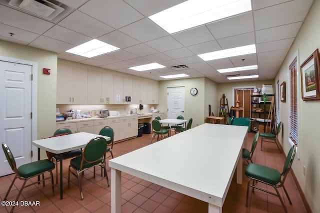 kitchen with a paneled ceiling, white cabinetry, and sink