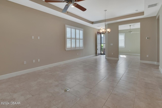 spare room featuring plenty of natural light, a raised ceiling, and ceiling fan with notable chandelier