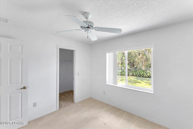 744 Hawks Ridge Rd, Port Orange, FL 32127 - unfurnished bedroom with light colored carpet, a spacious closet, a textured ceiling, a closet, and a ceiling fan
