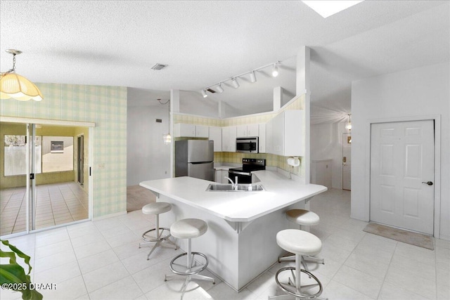744 Hawks Ridge Rd, Port Orange, FL 32127 - kitchen featuring appliances with stainless steel finishes, light countertops, a peninsula, light tile patterned floors, and wallpapered walls