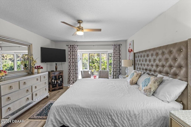 bedroom featuring hardwood / wood-style flooring, a textured ceiling, multiple windows, and ceiling fan