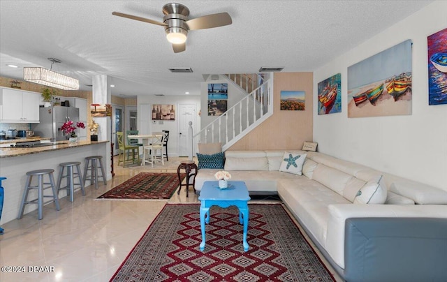 tiled living room featuring ceiling fan and a textured ceiling