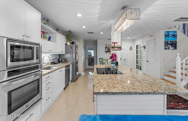 kitchen featuring white cabinets, stainless steel appliances, sink, and light stone countertops