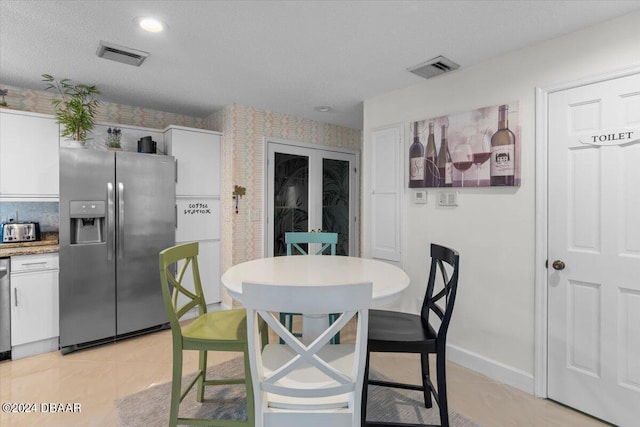 dining area with a textured ceiling and light tile patterned flooring