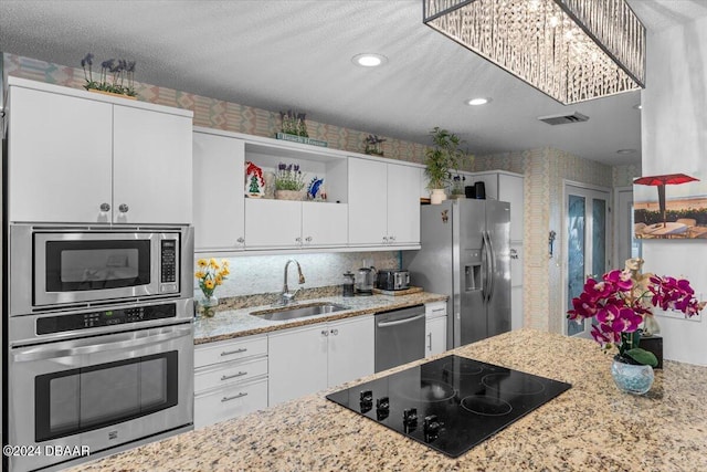 kitchen with light stone counters, white cabinetry, appliances with stainless steel finishes, a textured ceiling, and sink