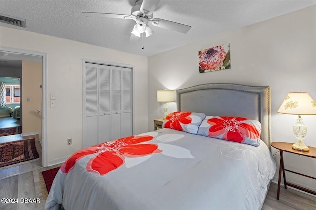 bedroom with a textured ceiling, hardwood / wood-style floors, ceiling fan, and a closet