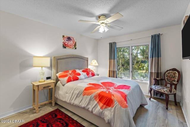 bedroom with wood-type flooring, ceiling fan, and a textured ceiling