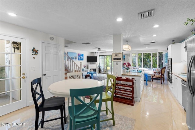 tiled dining area with a textured ceiling and ceiling fan