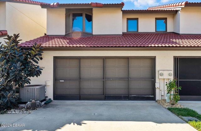 view of front of home with central air condition unit and a garage