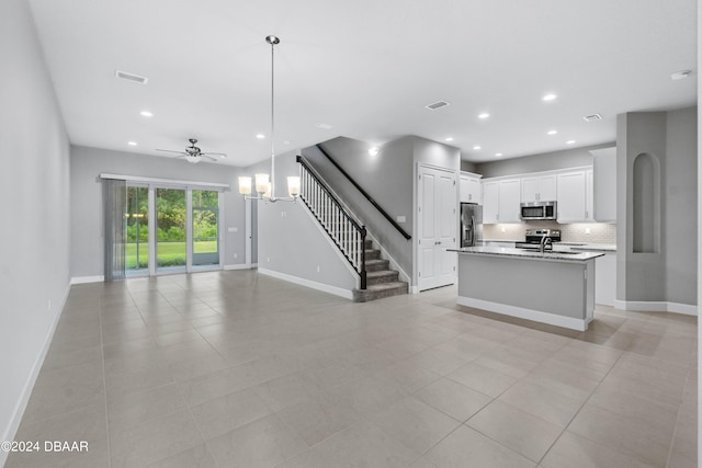 kitchen with white cabinetry, sink, appliances with stainless steel finishes, an island with sink, and pendant lighting