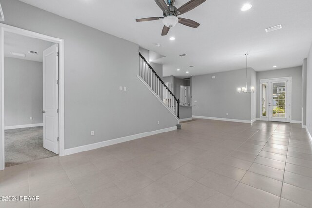 unfurnished living room with ceiling fan with notable chandelier