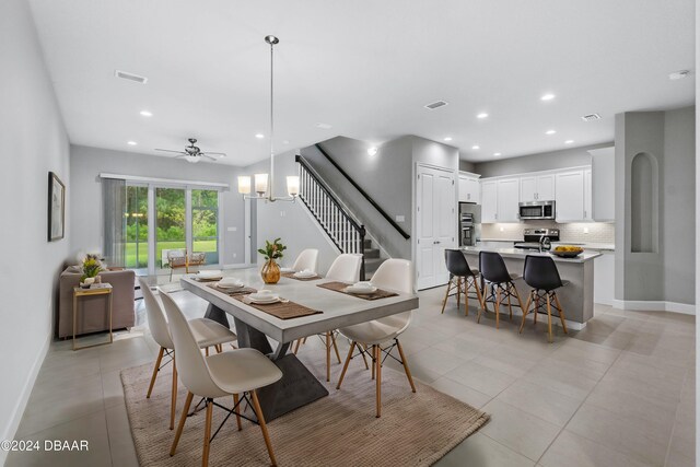 tiled dining room featuring ceiling fan with notable chandelier