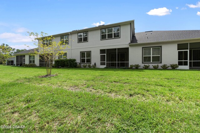 rear view of property with a sunroom and a lawn