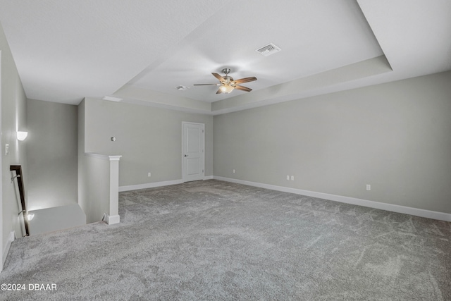 empty room featuring carpet, ceiling fan, and a raised ceiling