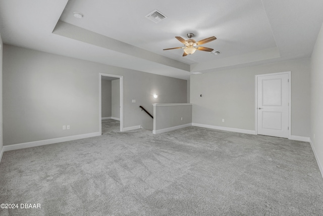 carpeted spare room featuring ceiling fan and a raised ceiling