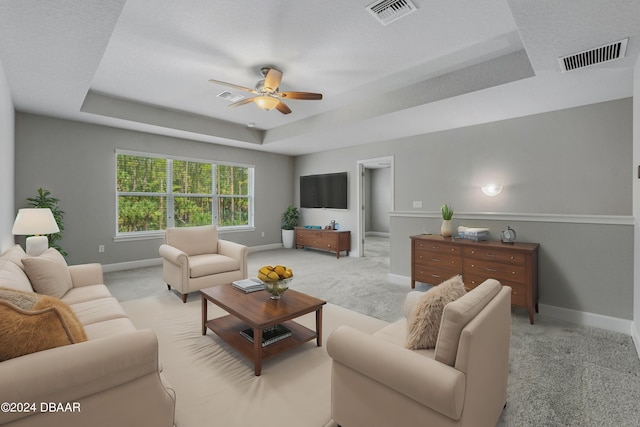 carpeted living room featuring ceiling fan and a tray ceiling