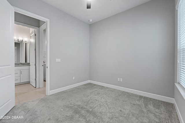 unfurnished bedroom featuring ensuite bath, ceiling fan, light colored carpet, and sink