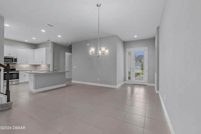 kitchen with a center island with sink, pendant lighting, an inviting chandelier, white cabinetry, and appliances with stainless steel finishes