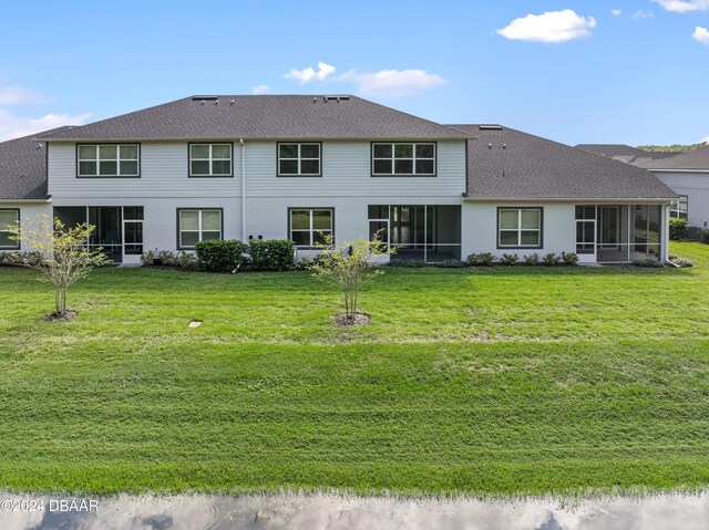 back of house featuring a sunroom and a lawn