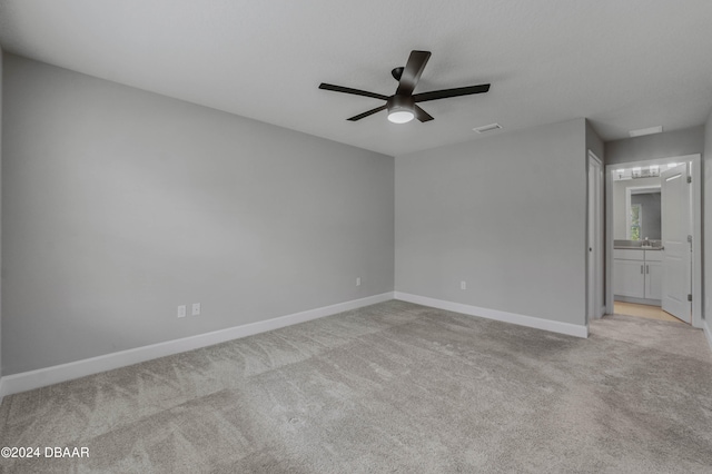 spare room with light carpet, ceiling fan, and sink