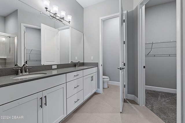 bathroom with tile patterned flooring, vanity, toilet, and a shower with shower door