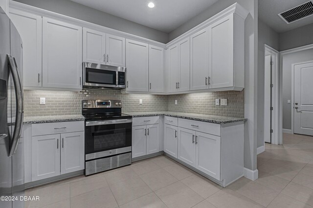 kitchen featuring light stone countertops, white cabinetry, decorative backsplash, and appliances with stainless steel finishes