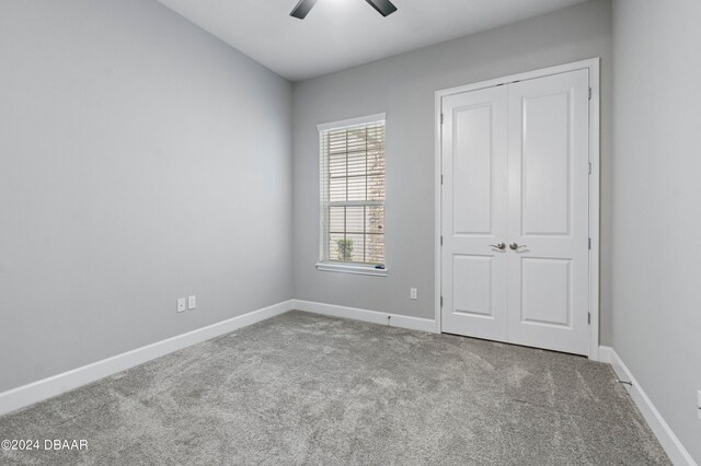 unfurnished bedroom featuring ceiling fan, light carpet, and a closet