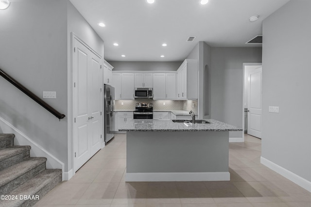 kitchen featuring sink, light stone counters, appliances with stainless steel finishes, white cabinets, and decorative backsplash