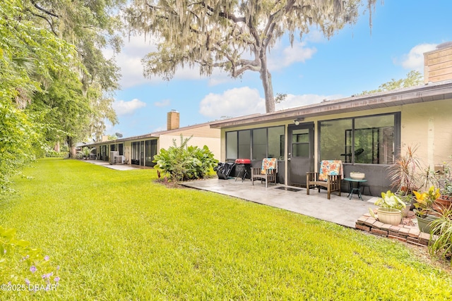 1237 Charter Oaks Cir, Holly Hill, FL 32117 - rear view of house with a chimney, a patio, a lawn, and stucco siding