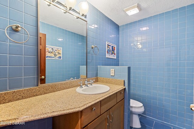 3726 S Atlantic Ave, New Smyrna Beach, FL 32169 - bathroom with tile walls, vanity, a textured ceiling, and tile patterned flooring