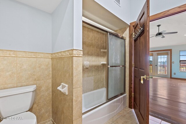 3726 S Atlantic Ave, New Smyrna Beach, FL 32169 - bathroom with ceiling fan, shower / bath combination with glass door, tile walls, and a wainscoted wall
