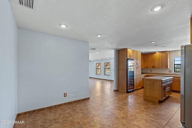 3726 S Atlantic Ave, New Smyrna Beach, FL 32169 - kitchen featuring plenty of natural light, a kitchen island, light countertops, freestanding refrigerator, and a textured ceiling