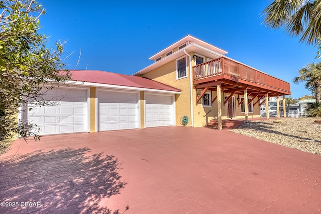 3726 S Atlantic Ave, New Smyrna Beach, FL 32169 - view of front facade with stucco siding, driveway, a wooden deck, and a metal roof