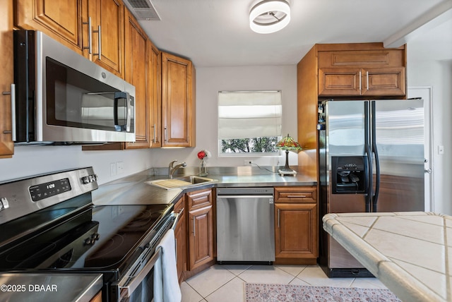 326 Flushing Ave, Daytona Beach, FL 32118 - kitchen with appliances with stainless steel finishes, brown cabinets, a sink, and light tile patterned flooring