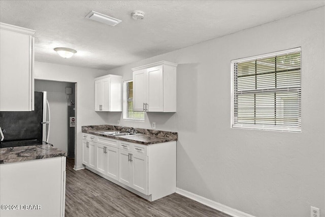 317 Reva St, Daytona Beach, FL 32114 - kitchen featuring freestanding refrigerator, dark wood-style flooring, white cabinetry, healthy amount of natural light, and a textured ceiling