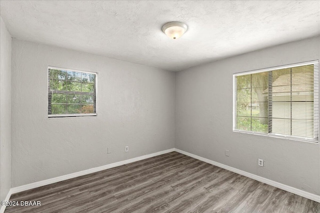 unfurnished room featuring a wealth of natural light, dark wood-type flooring, and a textured ceiling