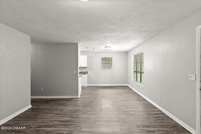 317 Reva St, Daytona Beach, FL 32114 - unfurnished living room with dark wood-style floors, a textured ceiling, a textured wall, and baseboards