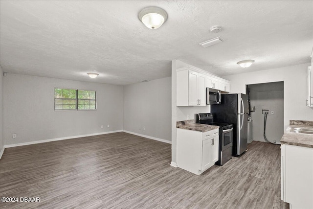 kitchen featuring white cabinets, stainless steel appliances, a textured ceiling, and light hardwood / wood-style flooring