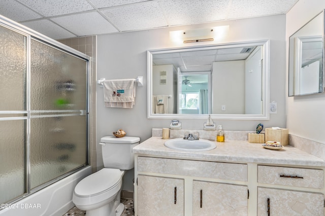 full bathroom with a paneled ceiling, vanity, toilet, combined bath / shower with glass door, and ceiling fan