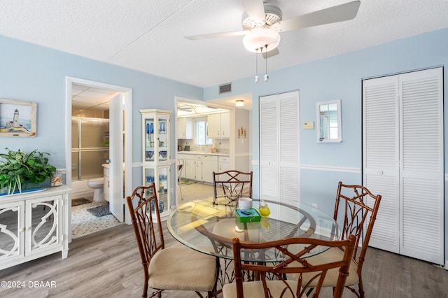 dining room with ceiling fan, a textured ceiling, and light hardwood / wood-style flooring