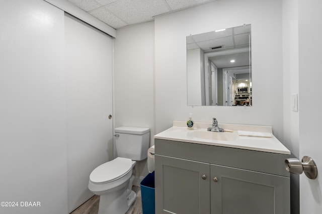 bathroom featuring toilet, a paneled ceiling, vanity, and hardwood / wood-style flooring