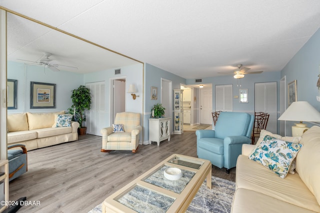 living room featuring hardwood / wood-style floors, ceiling fan, and a textured ceiling