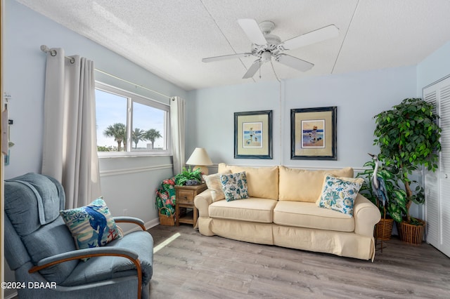 living room featuring ceiling fan, a textured ceiling, and light wood-type flooring